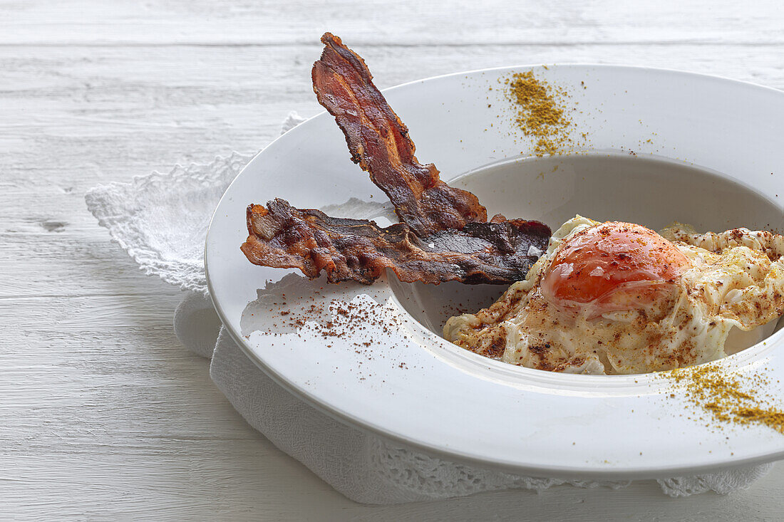 Overhead view of tasty eggs with fried bacon strips on plate