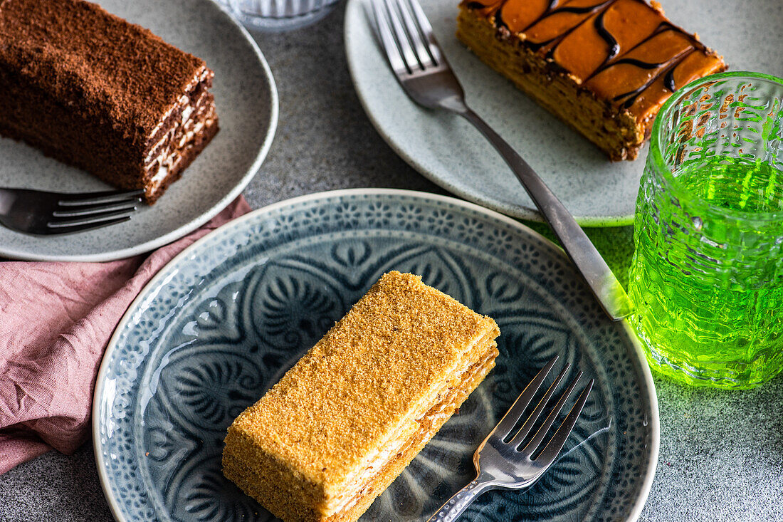 Von oben verschiedene hausgemachte Kuchenstücke auf Keramiktellern serviert