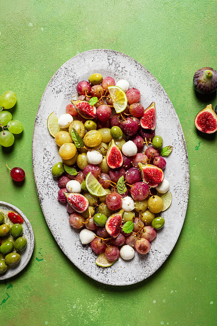 Frische reife Trauben, Oliven, Feigen und Mozzarella auf einem Teller auf einem grünen Tisch