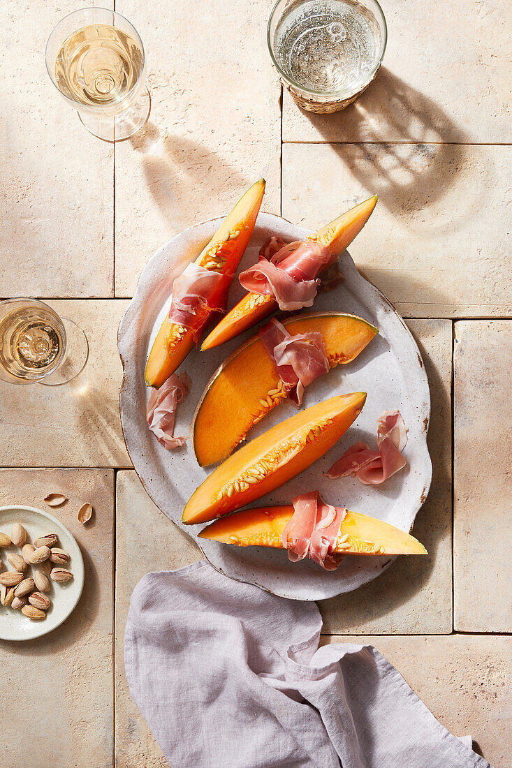 Draufsicht auf köstliche Melonenscheiben mit spanischem Schinken auf einem Teller auf dem Tisch