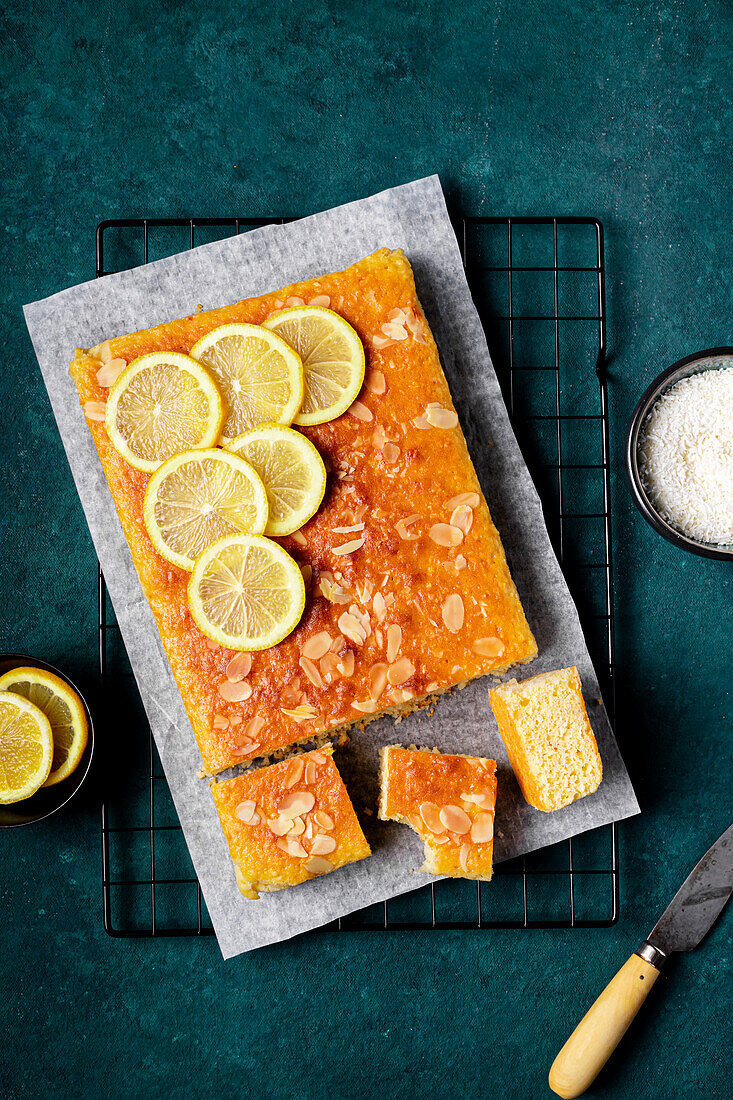 Square slice of tasty homemade lemon cake placed on metal rack in kitchen on blue background