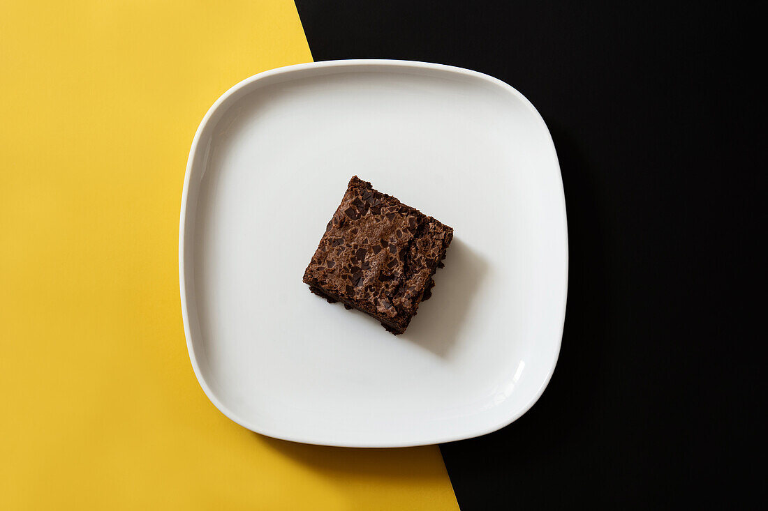 Stück frischer Brownie auf schwarzem und gelbem Hintergrund