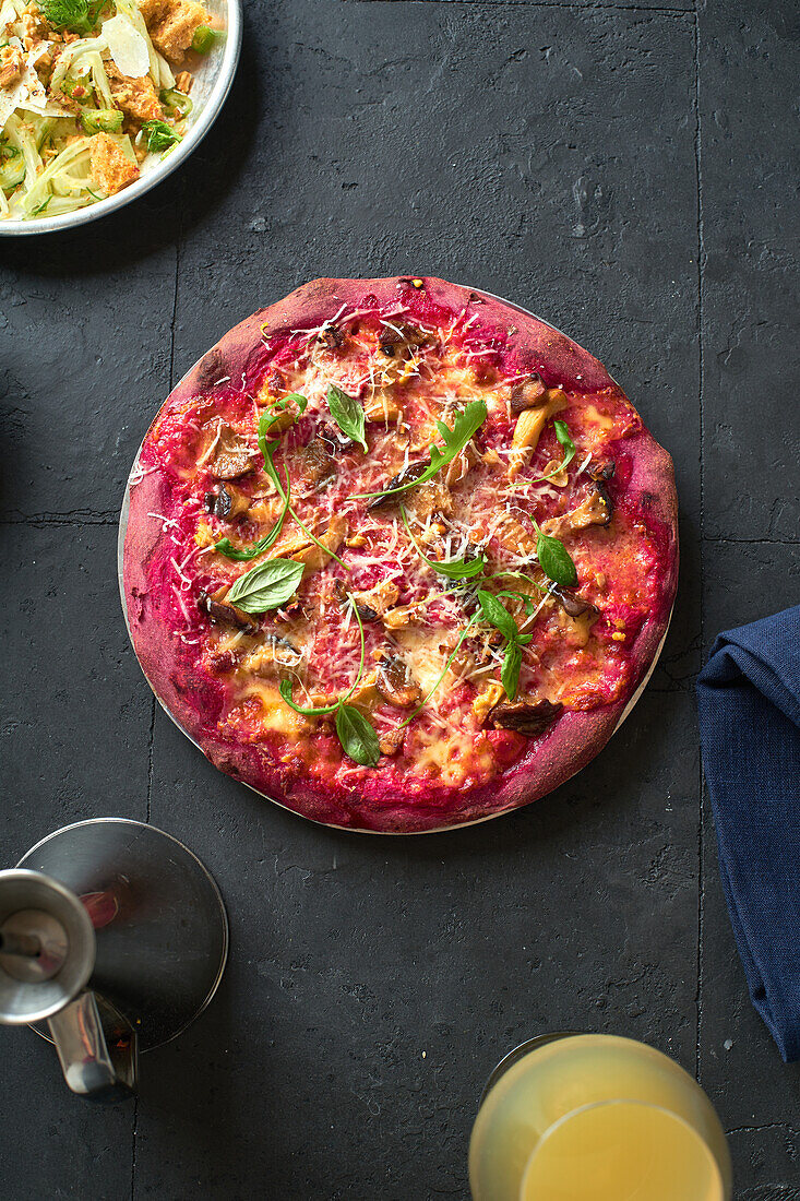 Purple colored rustic pizza with beetroot and vegetarian topping. Top view healthy food recipe