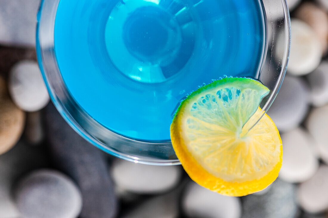 Glas mit blauem Kamikaze-Getränk auf Steinen in modernem Stil