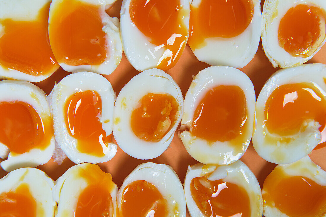 Draufsicht auf einen Vollbildhintergrund mit frischen weichgekochten Eiern, die in Reihen auf dem Tisch angeordnet sind