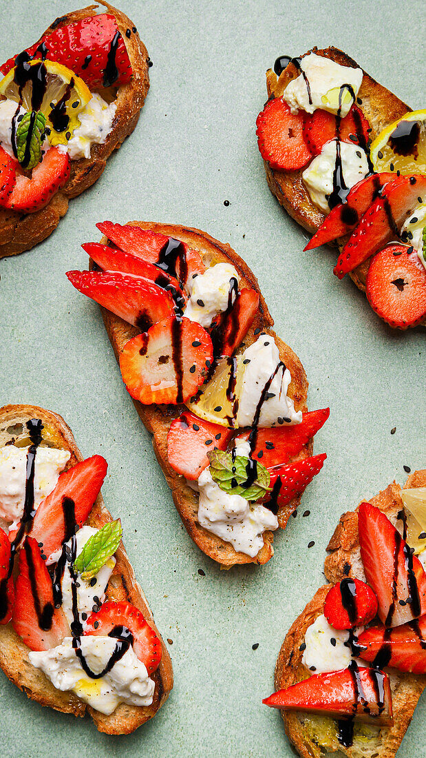 Top view of tasty fried toasts with strawberries and lemon slices served with burrata cheese and sauce