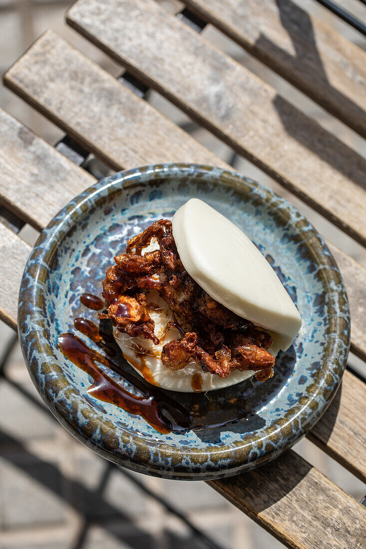 From above of delicious Japanese pan bao bun with fried soft shell crab served on corner of table on terrace of restaurant