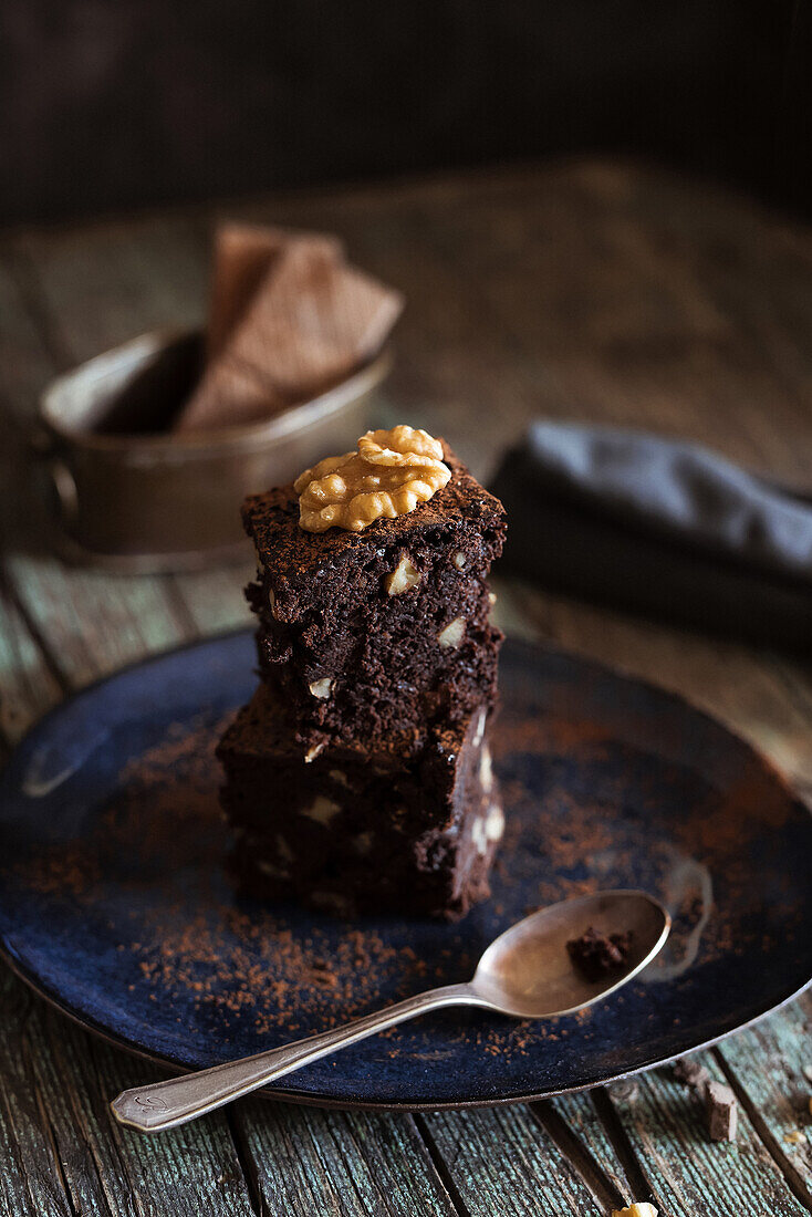 Detail of Piece of brownie cake with walnuts on a dish on wood background