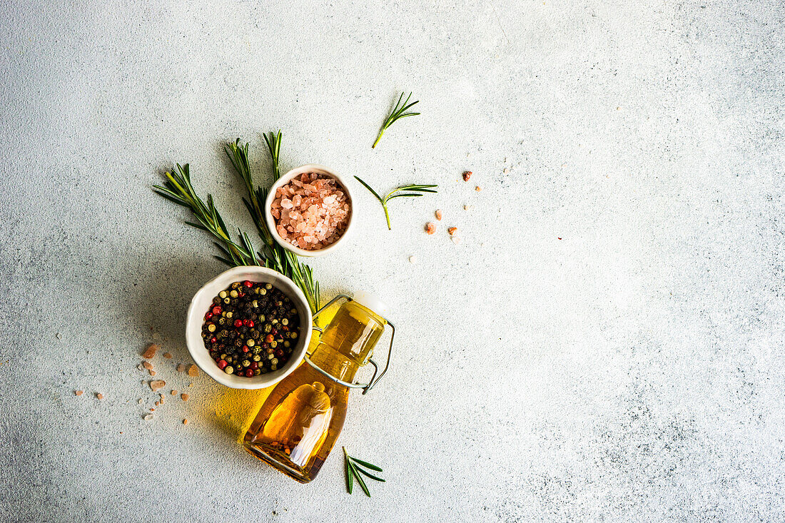 From above cooking concept with spices, olive oil and rosemary herb on concrete background