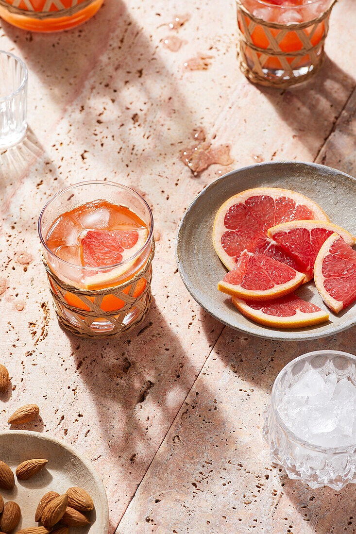 Hoher Blickwinkel auf einen blutigen Margarita-Cocktail mit Grapefruitsaft, der an einem sonnigen Sommertag auf dem Tisch neben Eiswürfeln steht
