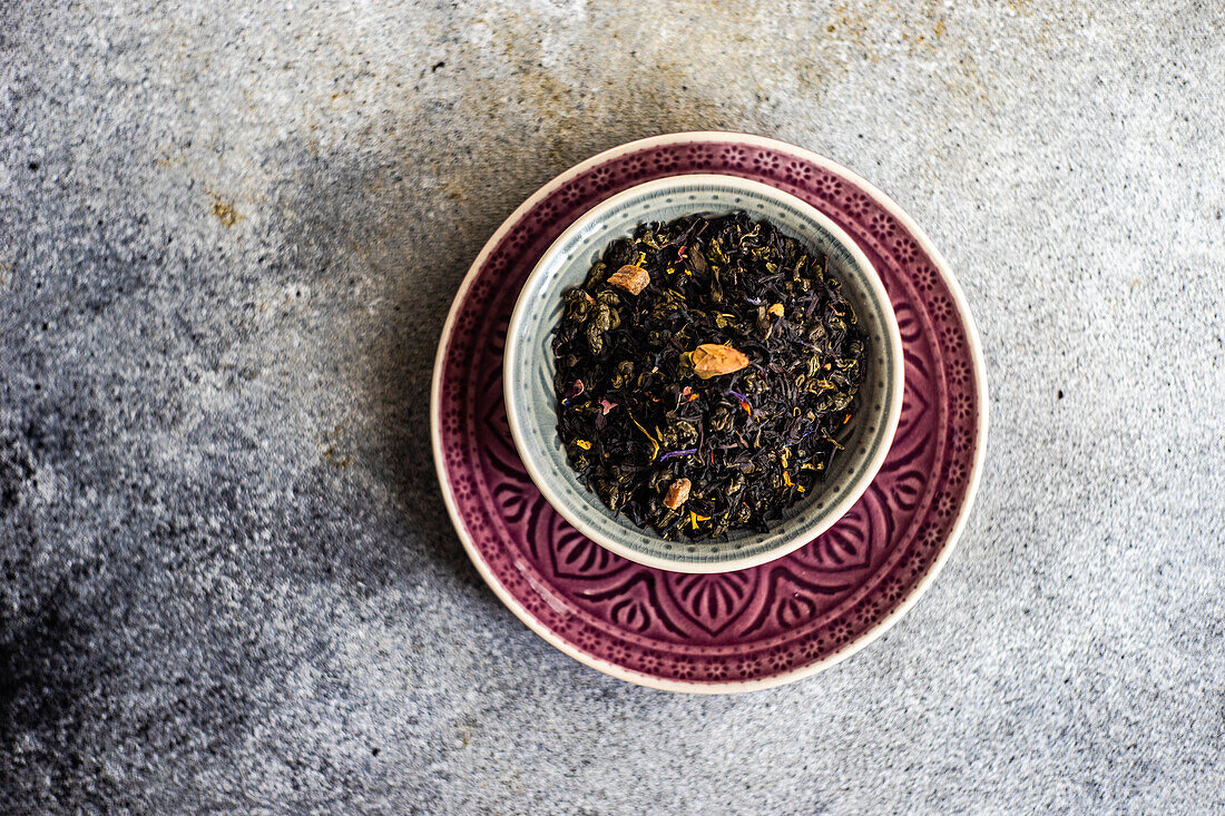 From above green sencha tea leaves with pieces of mango on concrete background