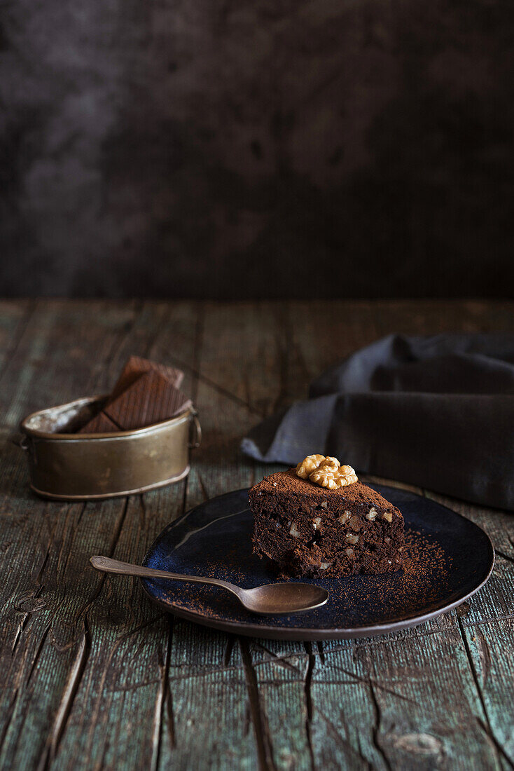 Detail of Piece of brownie cake with walnuts on a dish on wood background
