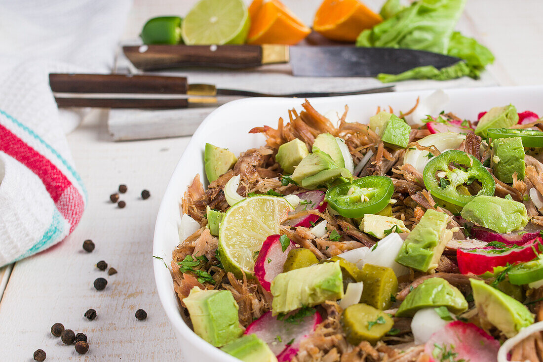 Cuban bowl with pulled meat and chopped avocado with jalapeno and radish and lime served in white ceramic bowl