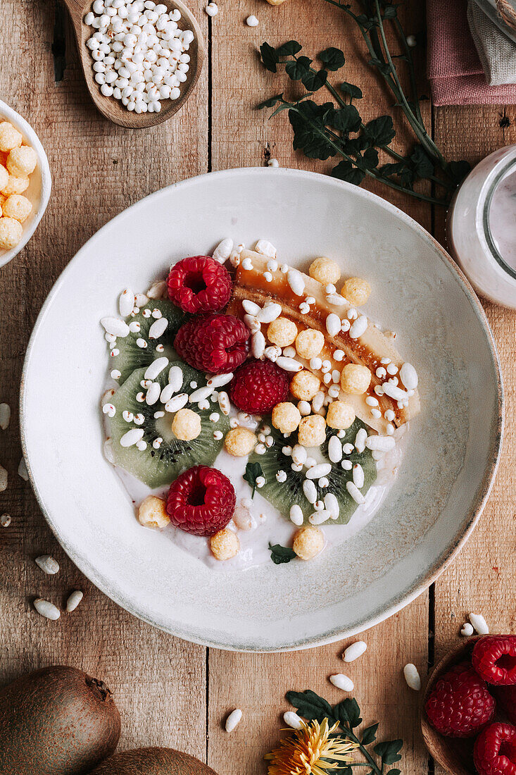 Blick von oben auf eine Schale mit frischen Früchten und Beeren auf einem rustikalen Holztisch