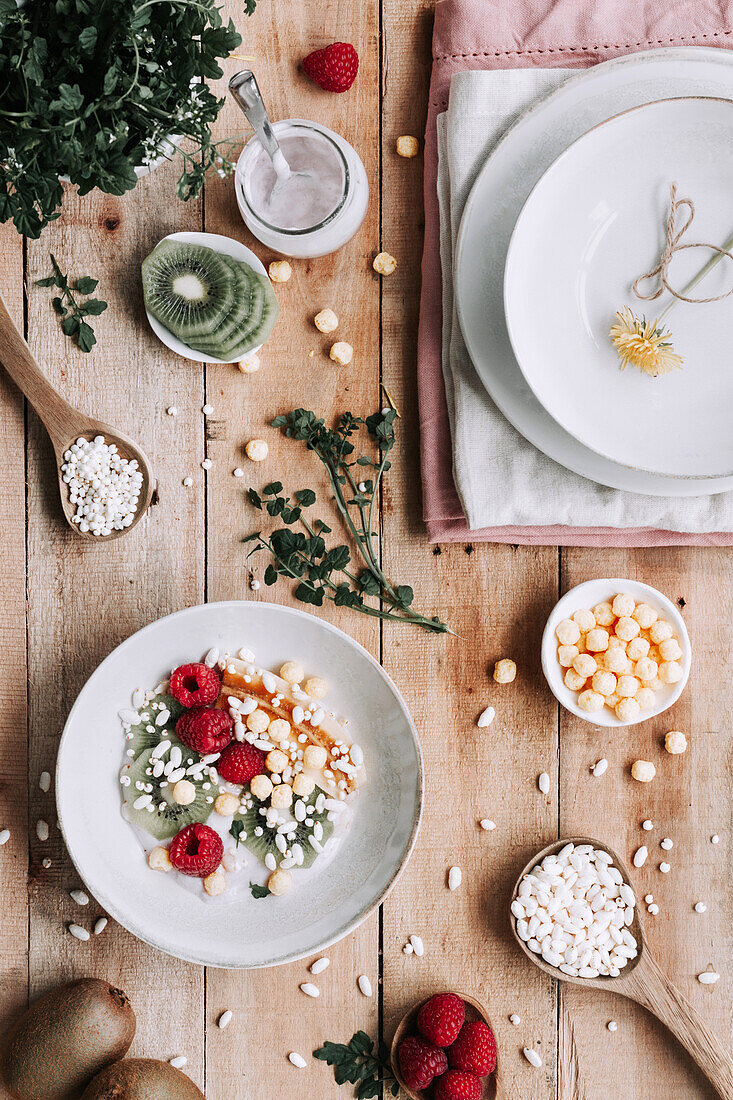 Blick von oben auf eine Schale mit frischen Früchten und Beeren auf einem rustikalen Holztisch