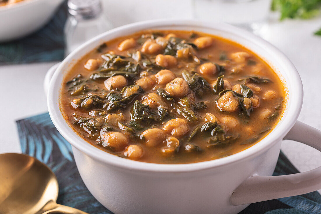 High angle of bowl with tasty chickpea soup served for lunch on paper napkin near spoon