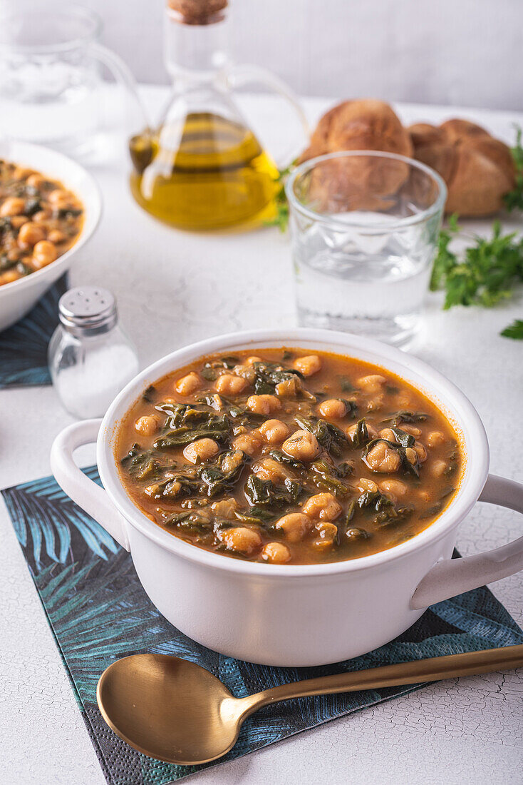 High angle of bowl with tasty chickpea soup served for lunch on paper napkin near spoon