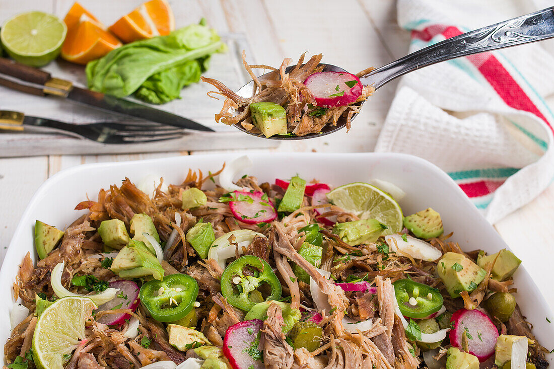 Kubanische Schale mit Pulled Meat und gehackter Avocado mit Jalapeno, Rettich und Limette, serviert in einer weißen Keramikschale