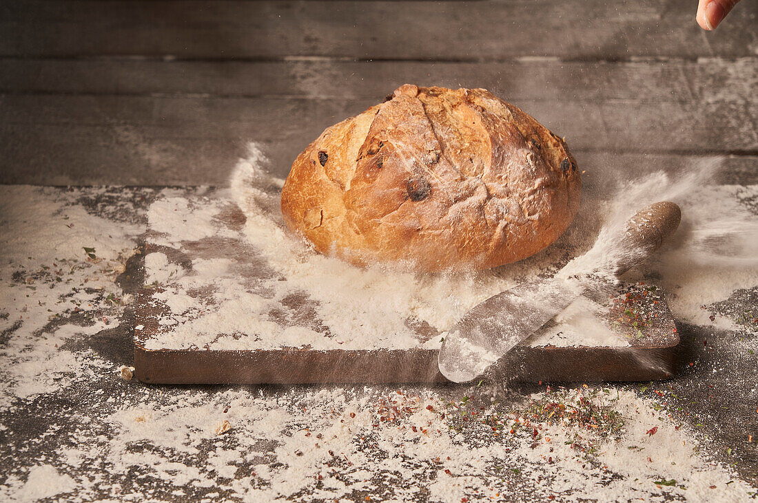Appetizing aromatic freshly baked homemade bread with raisins placed on wooden board sprinkled with flour