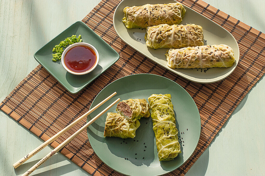 Cabbage spring rolls served on bamboo place mat near chopsticks