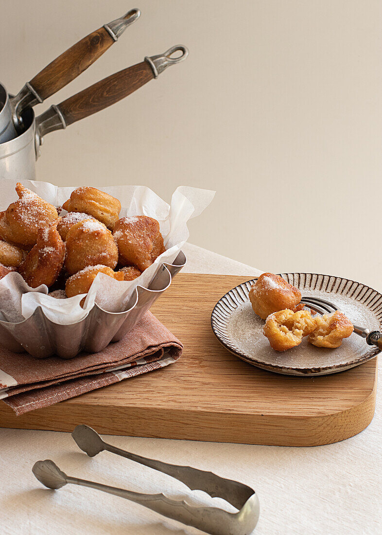 From above deep fried beignets doughnut placed on wooden tray on table in kitchen