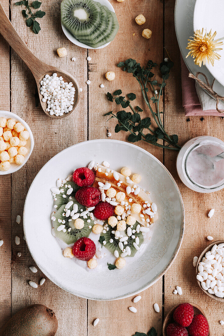 Blick von oben auf eine Schale mit frischen Früchten und Beeren auf einem rustikalen Holztisch