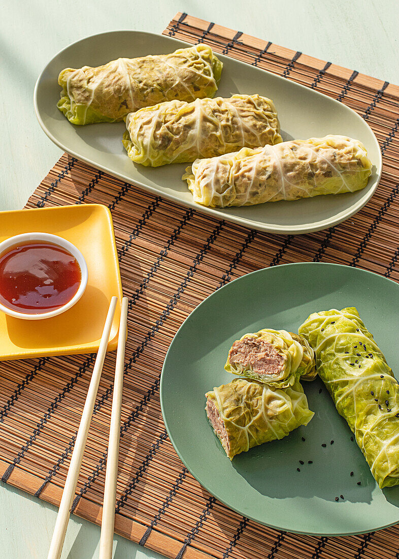 Cabbage spring rolls served on bamboo place mat near chopsticks