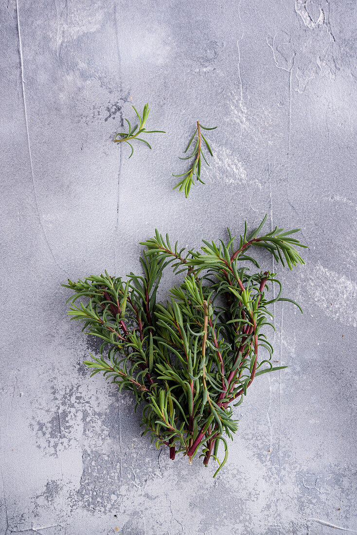 Top view of aromatic rosemary sprigs on rugged surface with spots