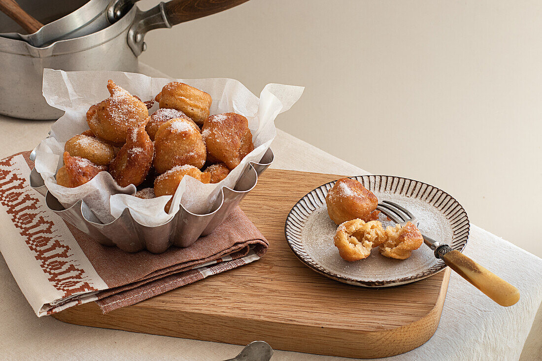 From above deep fried beignets doughnut placed on wooden tray on table in kitchen