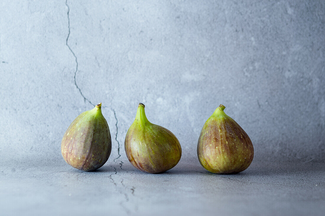 Ripe halved and whole figs placed with green leaf on wooden rustic table