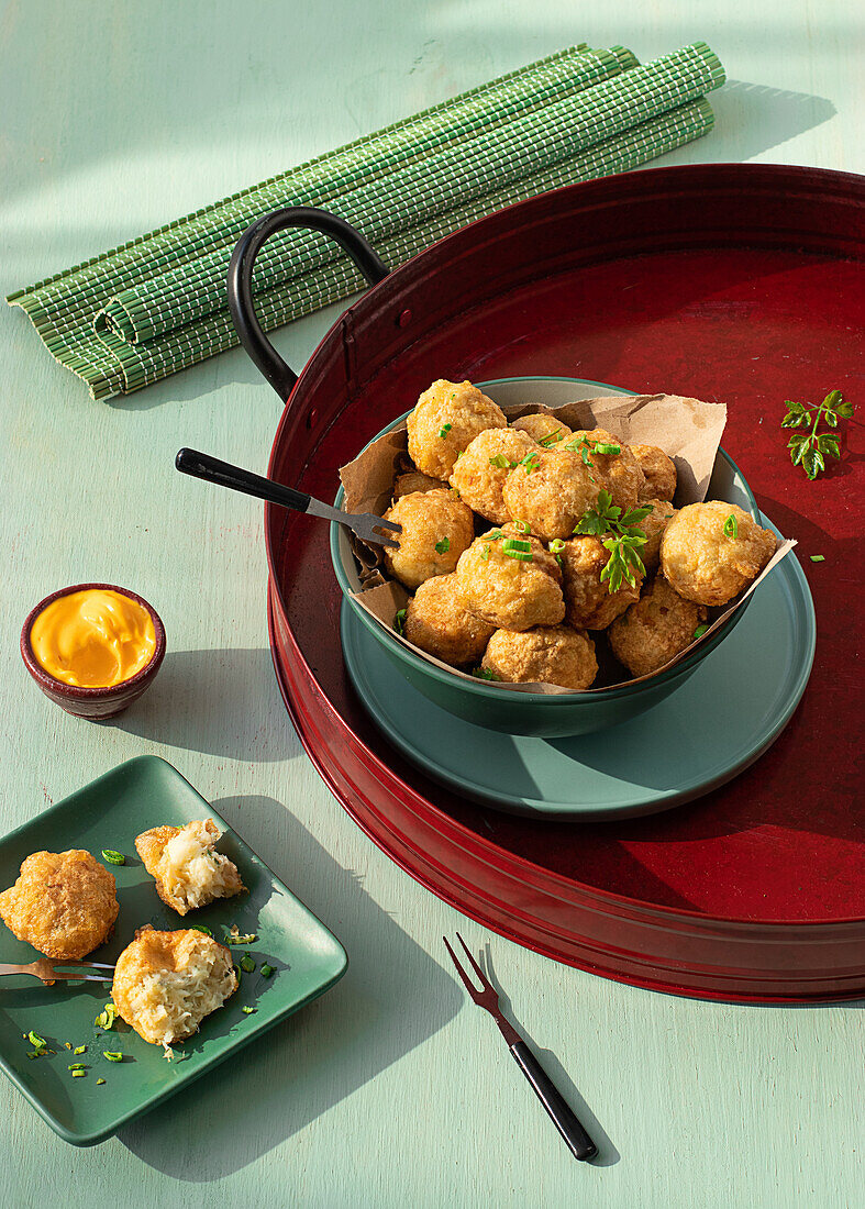 From above traditional codfish fritters server on tray with fresh herbs on green background
