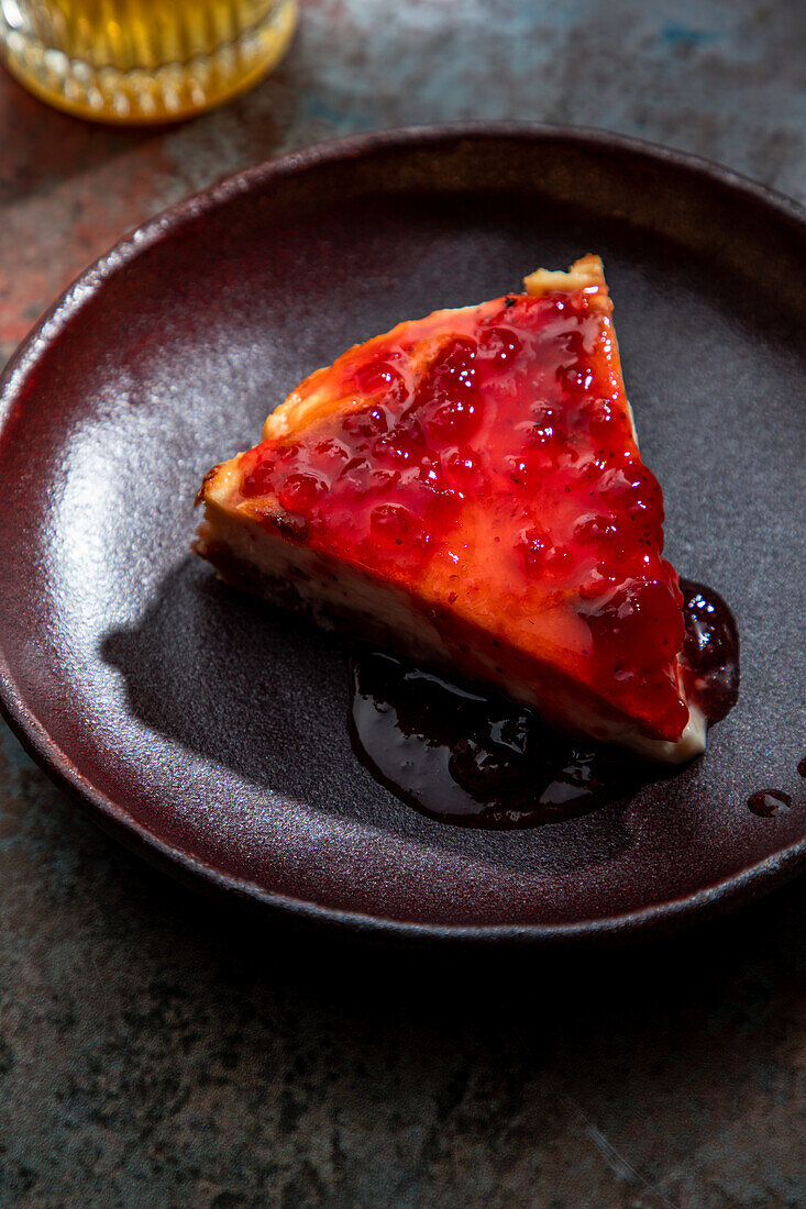 Von oben appetitlicher Kuchen mit Beerenmarmelade auf Keramikteller mit einem Glas Getränk mit Eis im Restaurant