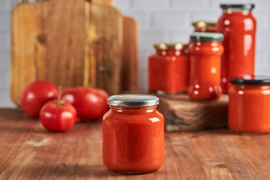 Verschlossenes Glas mit handgemachter Tomatensauce auf dem Tisch in der Küche zu Hause