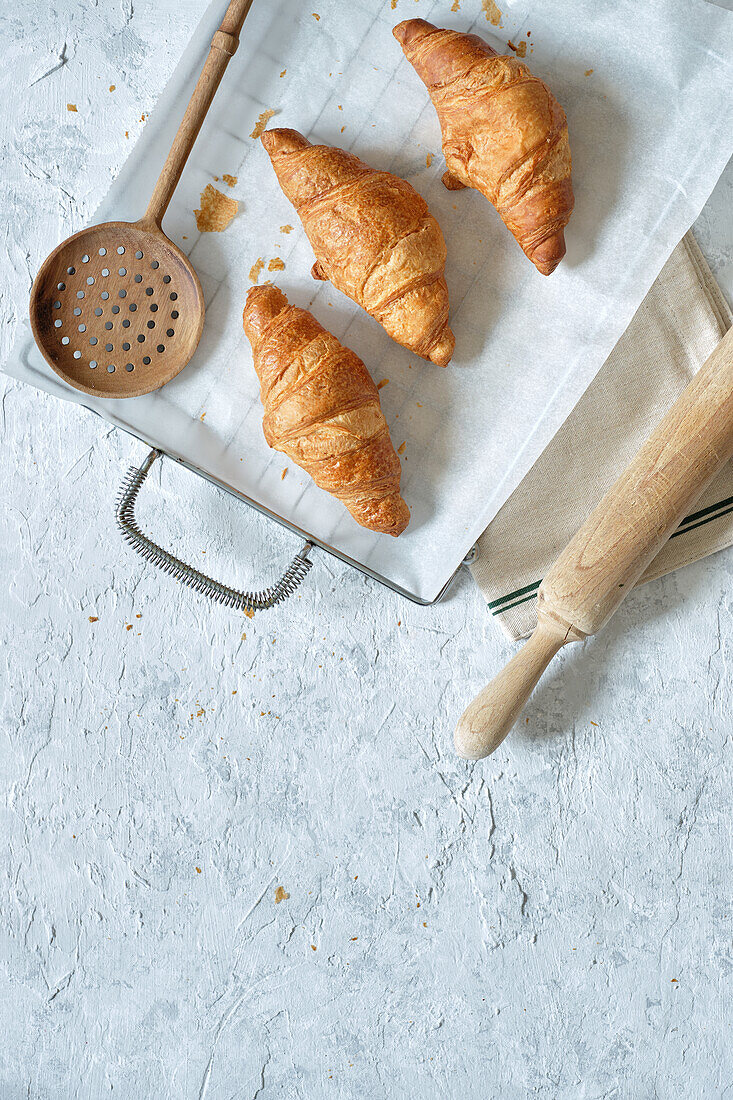 Top view of yummy fresh croissants placed on metal tray on table in kitchen