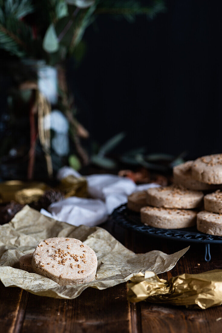 Ein Stapel appetitlicher süßer Butterkekse mit Haselnüssen wird auf einem Teller auf einem Holztisch mit festlichem Geschenkpapier und Bändern für die Weihnachtsfeier serviert
