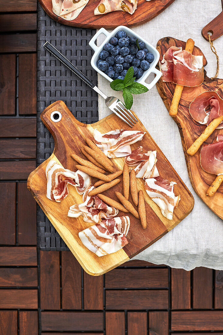 From above of assorted tasty appetizers served on table with tablecloth on terrace