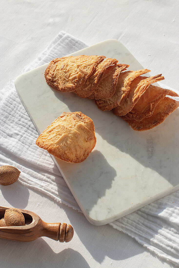 Top view of delicious Almond Tiles cookies placed on plate on tablecloth