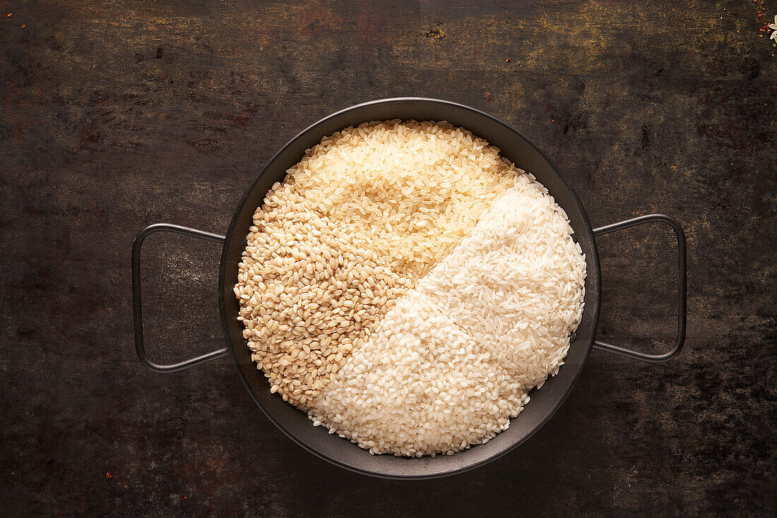 Schale mit verschiedenen Arten von getrocknetem Reis auf schwarzem Hintergrund von oben