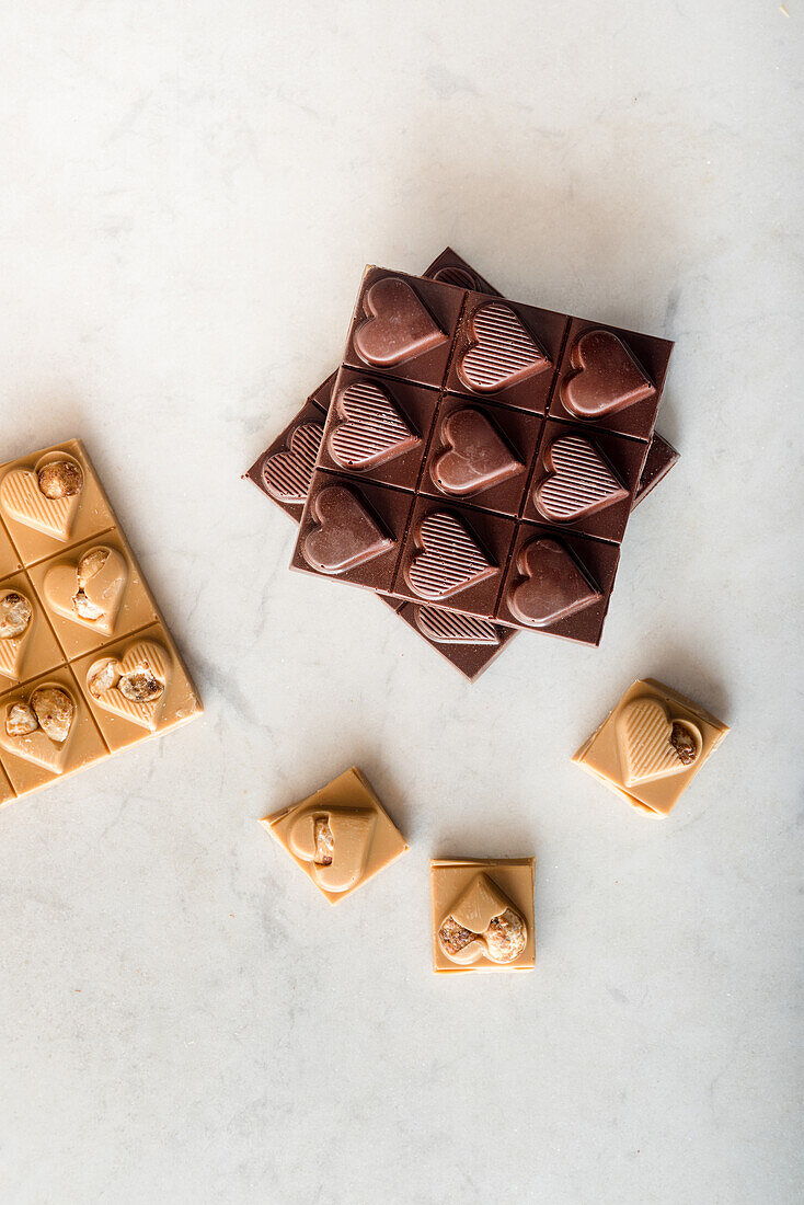 Top view of delicious chocolate candies with nuts in shape of heart scattered on white background