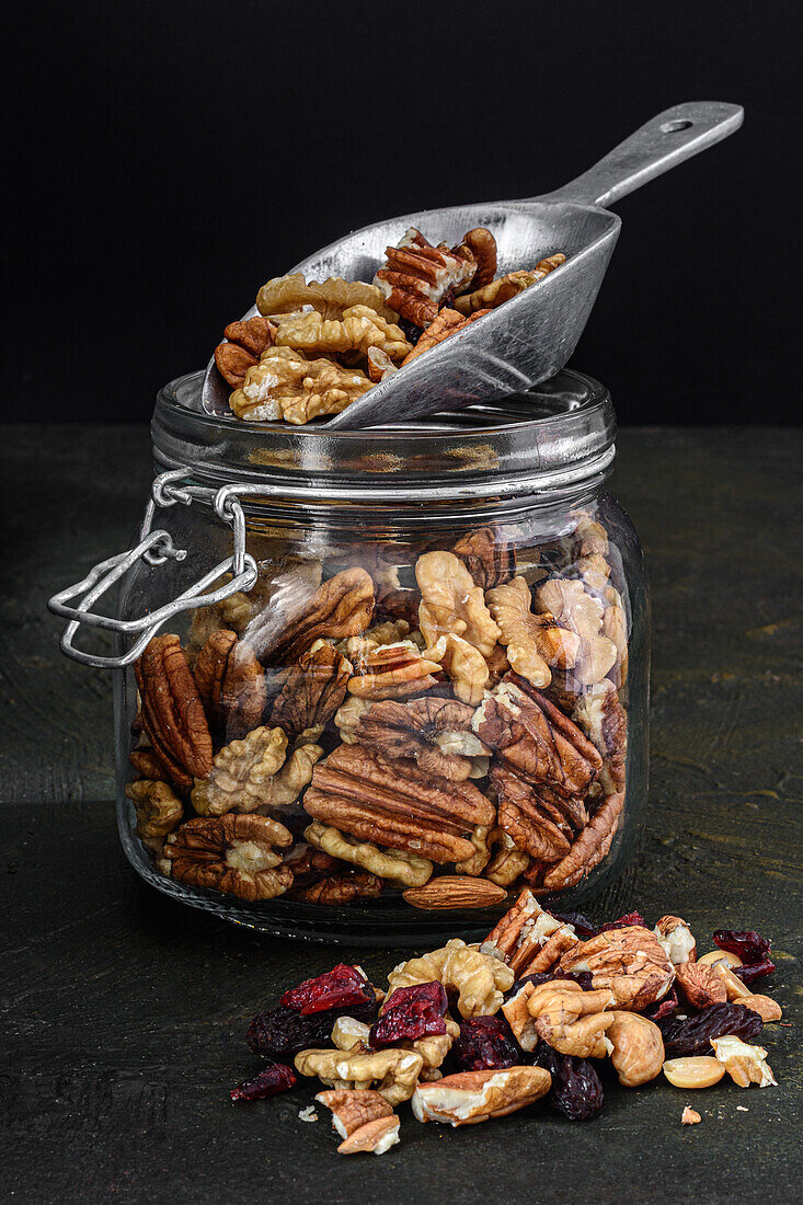 Glass jar with nuts and dried fruits on a dark rustic background