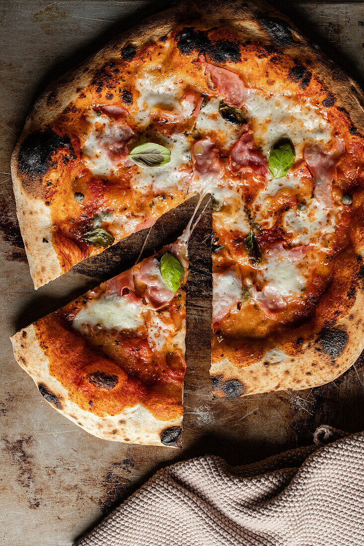 Draufsicht auf eine leckere Pizza mit Käse und Basilikum auf einer verbrannten Oberfläche