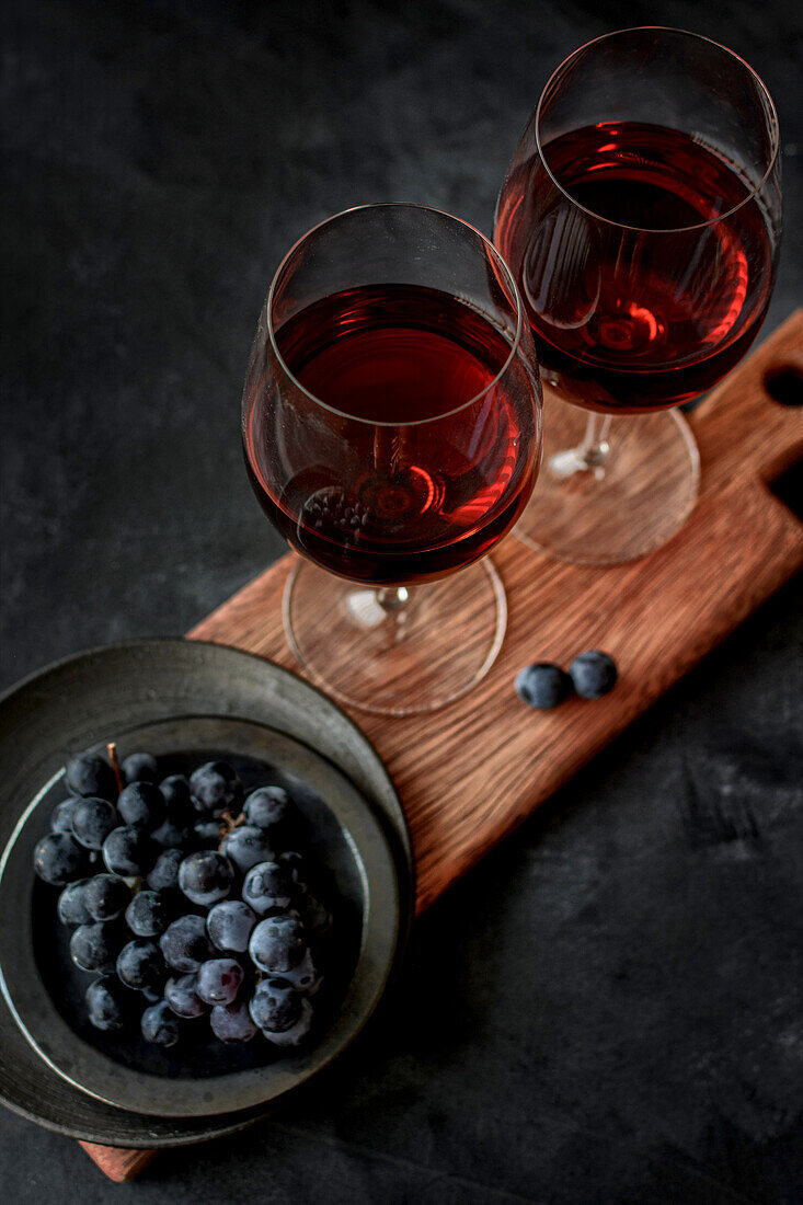 Von oben auf den Tisch gestelltes Weinglas mit frischen reifen Weintrauben im Studio auf schwarzem Hintergrund