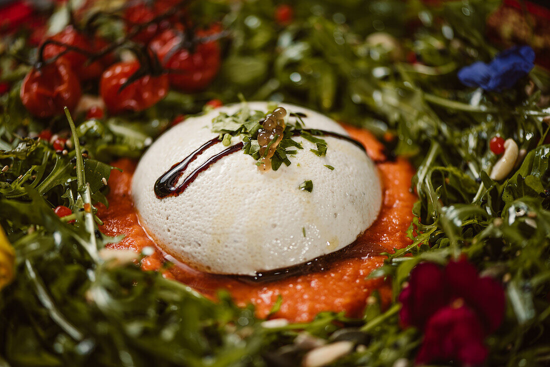 Yummy burrata cheese on cold tomato cream with arugula leaves and cherry tomatoes with truffles and peanuts