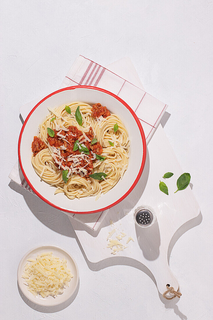 Top view of plate with spaghetti Bolognese pasta with tomatoes sauce in white table background