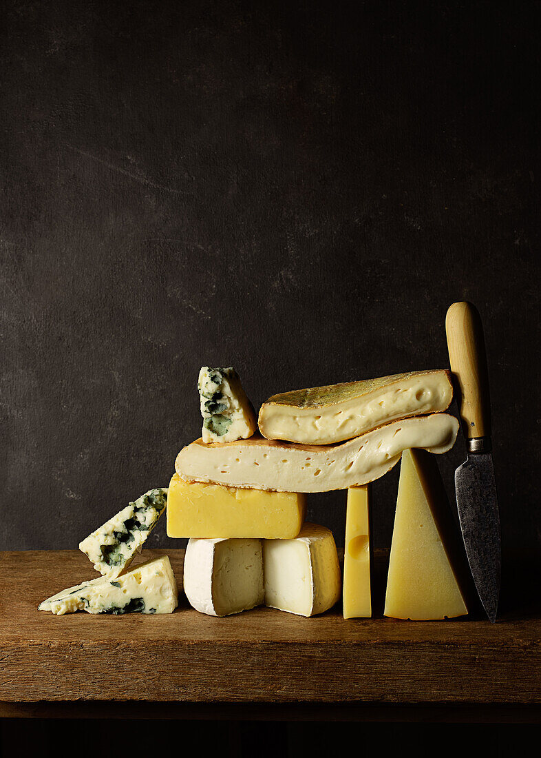 Various cut cheese on wooden board placed on wooden table