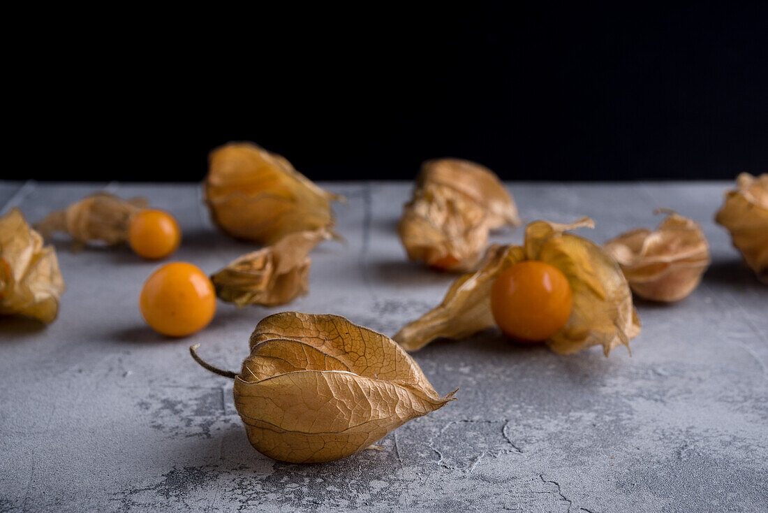 Similar small cape gooseberries with calyces on rugged surface with spots