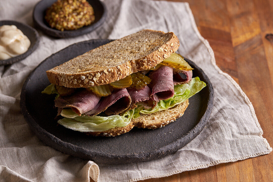 Nahaufnahme eines leckeren Sandwiches mit Pastrami, Salat, Schinken und Gurken