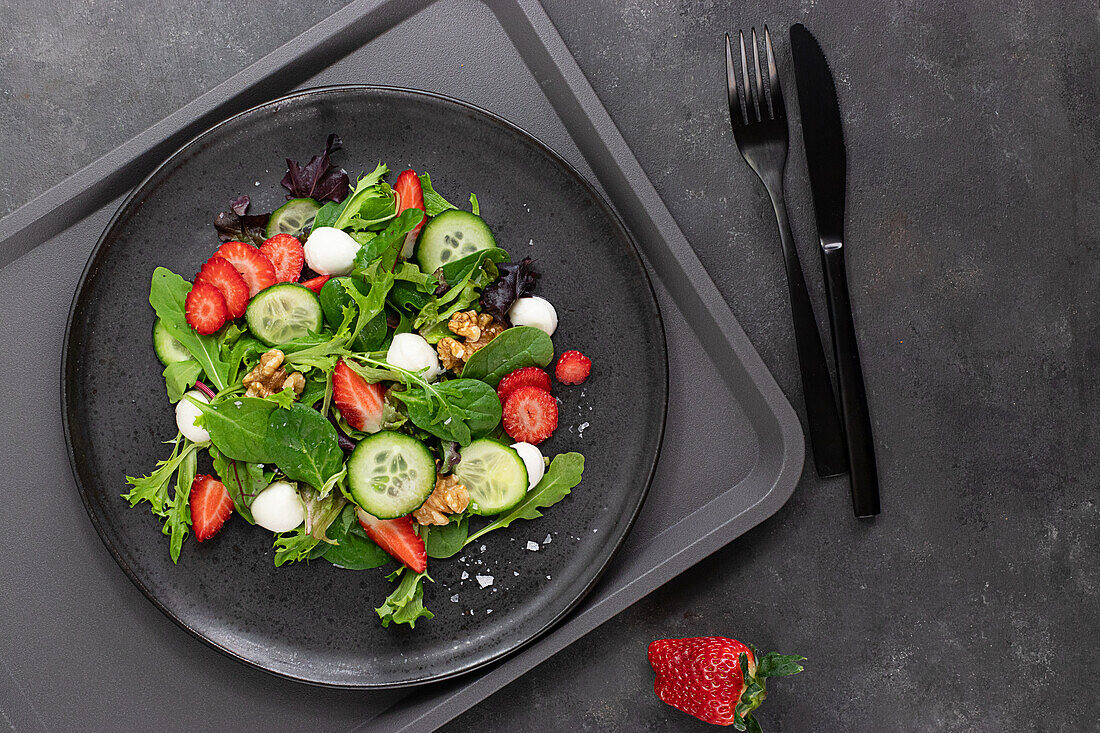 Selbstbedienungsrestaurant mit einem Teller mit einem sommerlichen Erdbeer- und Gurkensalat auf einem Tablett