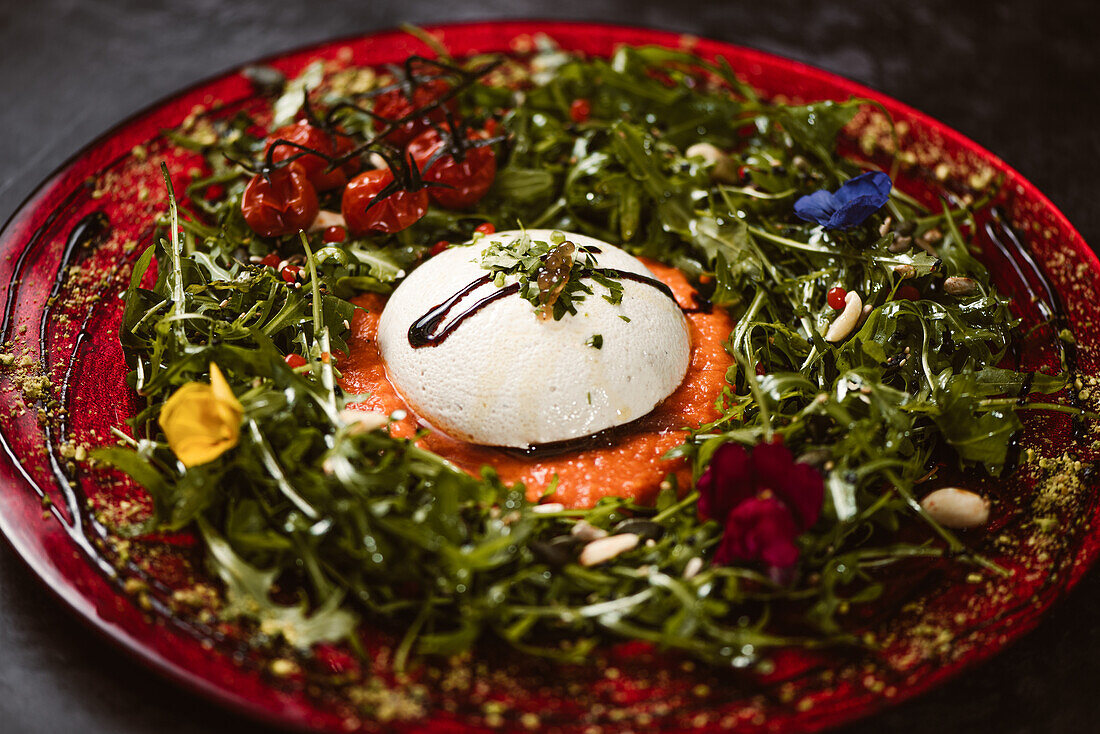 Yummy burrata cheese on cold tomato cream with arugula leaves and cherry tomatoes with truffles and peanuts