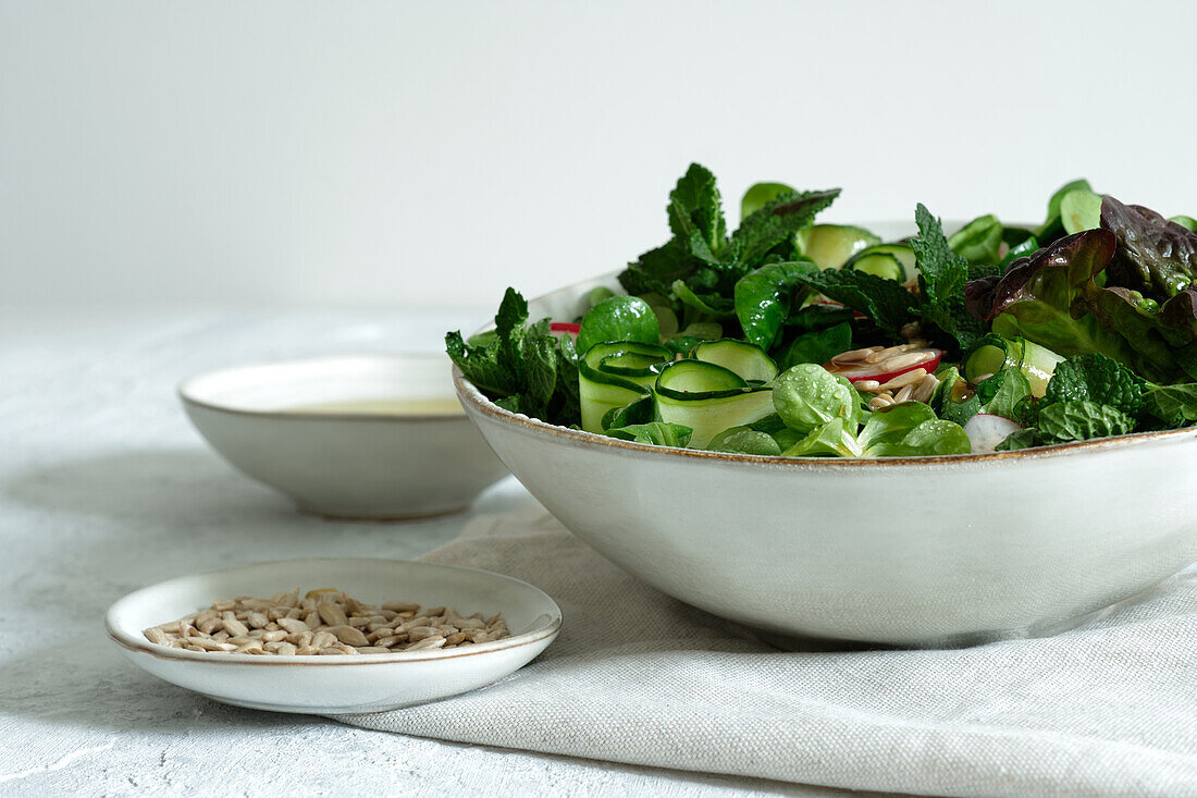 Fresh healthy vegetable salad in bowl served on table with olive oil and sunflower seeds